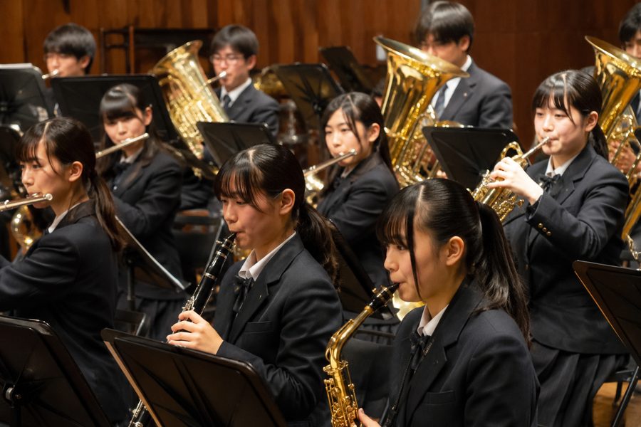 ホールの舞台で合奏する制服姿の吹奏楽部員たち